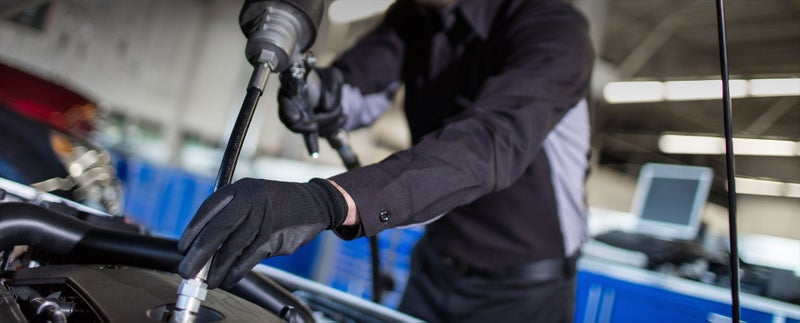Close up image of service technician working on a vehicle - Bergstrom GMC of Manitowoc in MANITOWOC WI